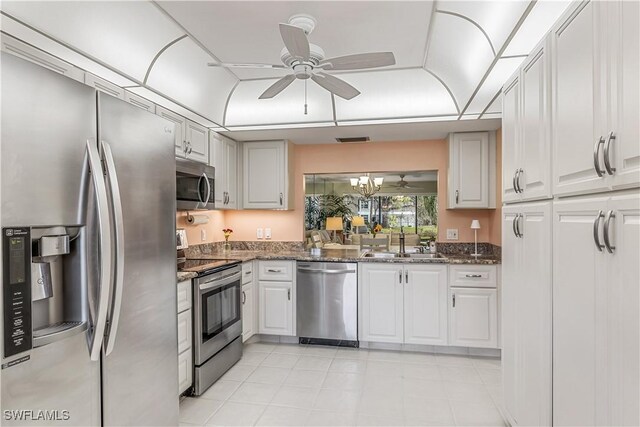 kitchen with stainless steel appliances, white cabinets, dark stone counters, and sink