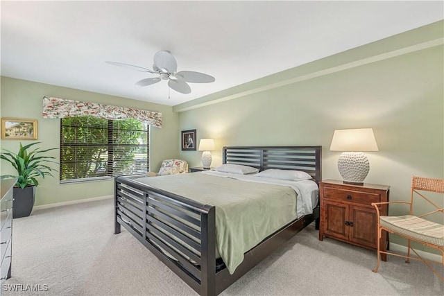 bedroom with light carpet, ceiling fan, and baseboards