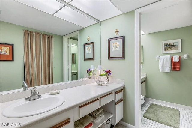 bathroom featuring toilet, tile patterned flooring, vanity, and baseboards