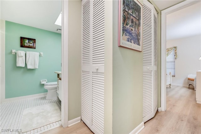 bathroom featuring a closet, toilet, and baseboards