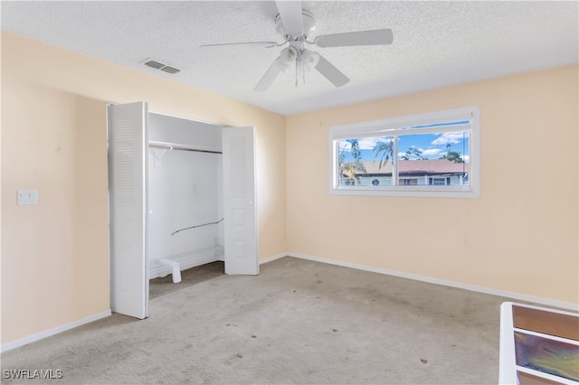 unfurnished bedroom featuring a closet, ceiling fan, light carpet, and a textured ceiling