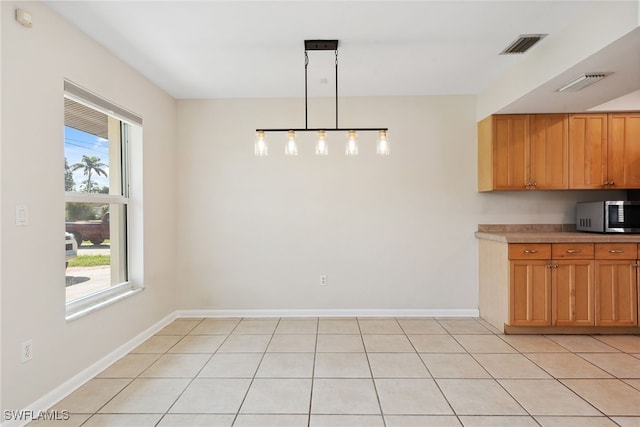 kitchen with hanging light fixtures, a healthy amount of sunlight, and light tile patterned floors