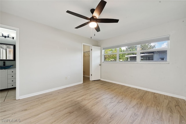 unfurnished bedroom with ceiling fan, connected bathroom, light hardwood / wood-style flooring, a closet, and a walk in closet