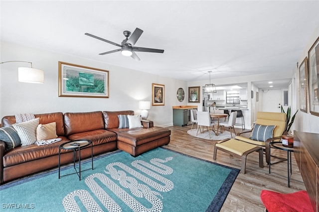 living room with light hardwood / wood-style floors and ceiling fan with notable chandelier