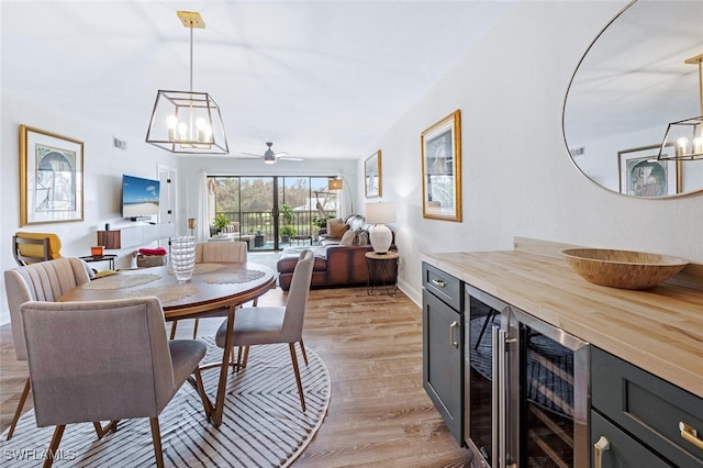 dining room with ceiling fan, light wood-type flooring, and beverage cooler