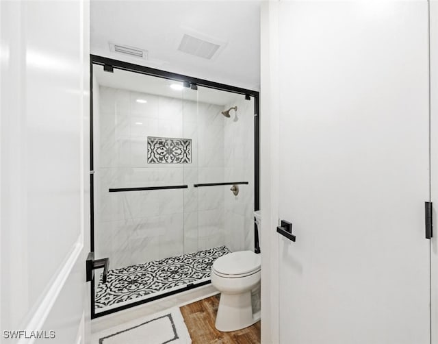 bathroom with a shower with door, toilet, and hardwood / wood-style flooring