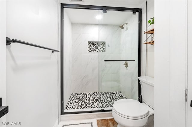 bathroom with toilet, a shower with shower door, and wood-type flooring