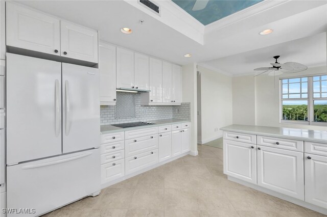 kitchen with black electric stovetop, crown molding, white cabinets, white fridge, and ceiling fan