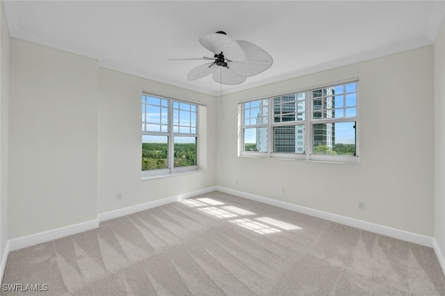 carpeted spare room with a wealth of natural light, crown molding, and ceiling fan