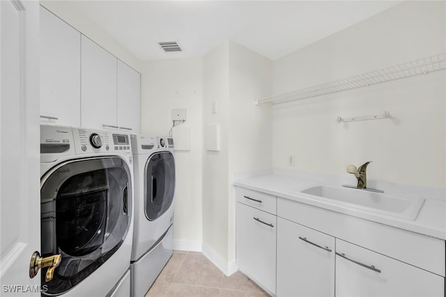 clothes washing area featuring sink, light tile patterned flooring, separate washer and dryer, and cabinets