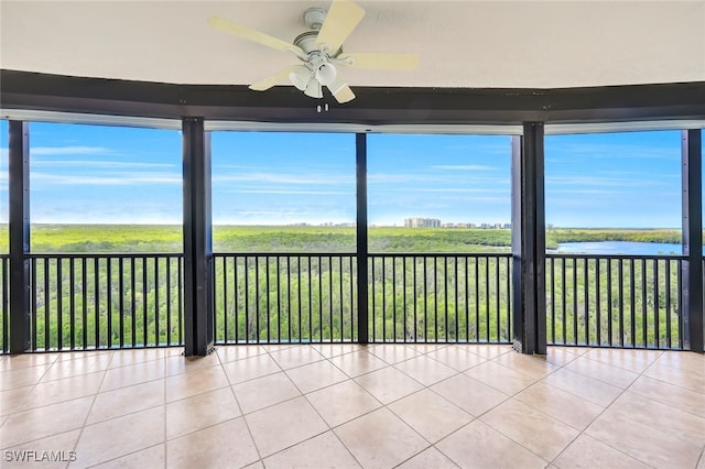 unfurnished sunroom with a water view, ceiling fan, and a healthy amount of sunlight