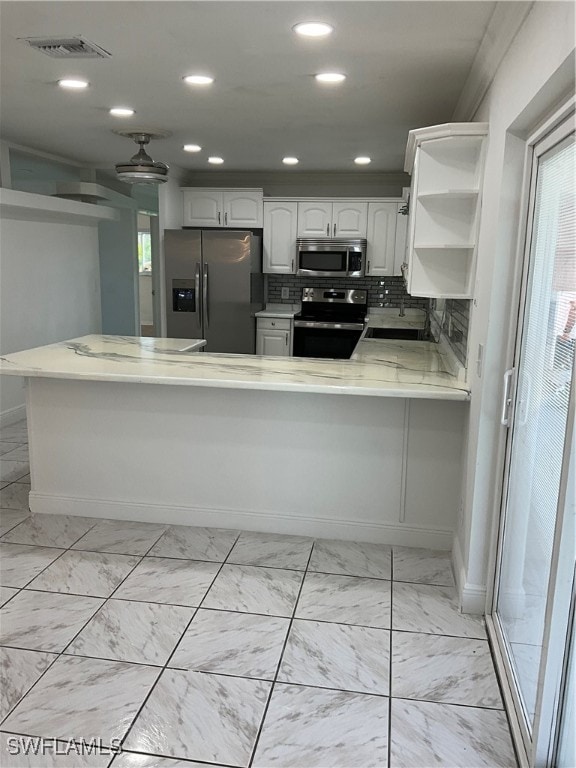 kitchen with white cabinetry, kitchen peninsula, stainless steel appliances, and backsplash