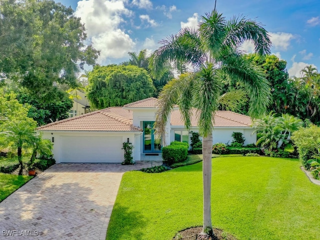 view of front of home featuring a front lawn, stucco siding, a tiled roof, and an attached garage