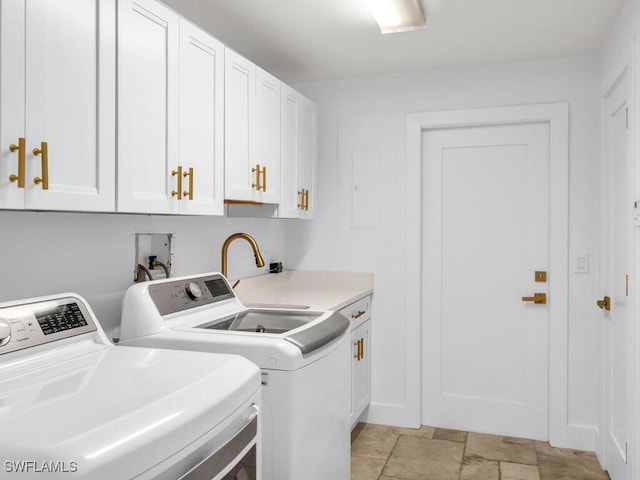 laundry room featuring stone finish flooring, washing machine and clothes dryer, and cabinet space