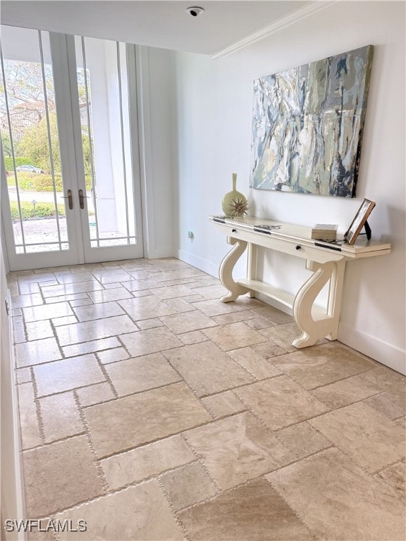 interior space with stone tile flooring, french doors, and baseboards