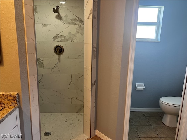 bathroom with tile patterned flooring, vanity, toilet, and tiled shower