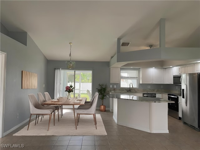 kitchen with sink, appliances with stainless steel finishes, decorative light fixtures, light tile patterned flooring, and white cabinetry