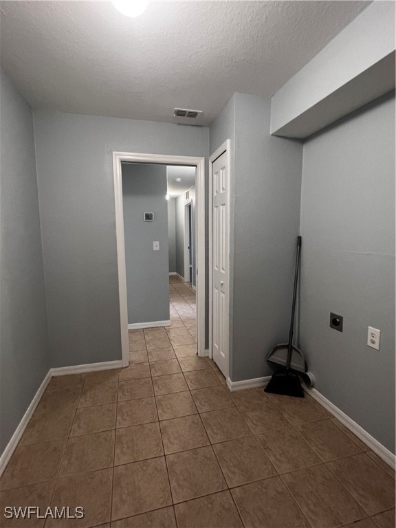 laundry room with hookup for an electric dryer, a textured ceiling, and tile patterned floors