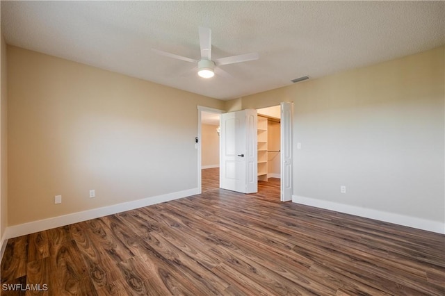 unfurnished bedroom with baseboards, a closet, a spacious closet, visible vents, and wood finished floors