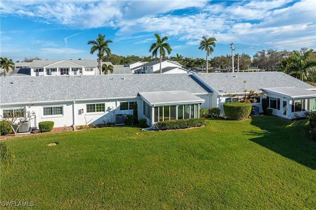 back of property featuring a yard, central AC unit, stucco siding, and a sunroom
