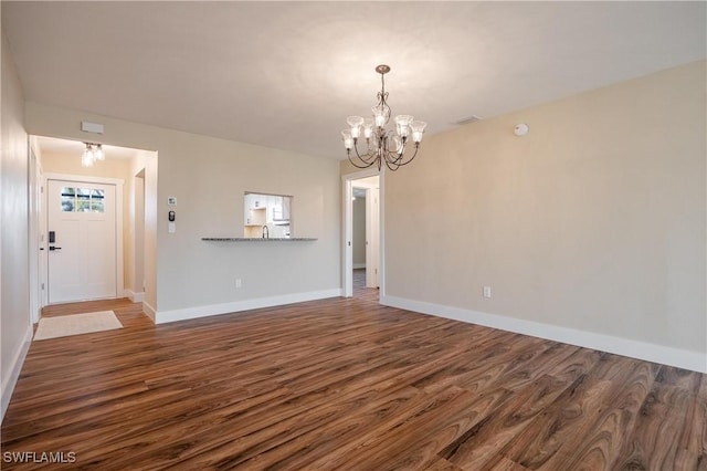unfurnished dining area with an inviting chandelier, baseboards, and dark wood-style flooring