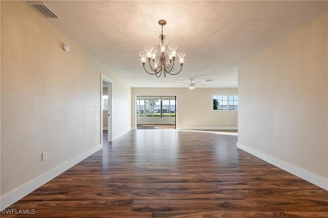 unfurnished dining area featuring ceiling fan with notable chandelier, baseboards, dark wood finished floors, and visible vents