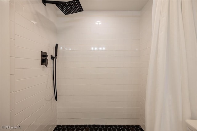 full bathroom featuring toilet and tiled shower