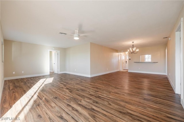 unfurnished room featuring dark wood-type flooring, visible vents, ceiling fan with notable chandelier, and baseboards