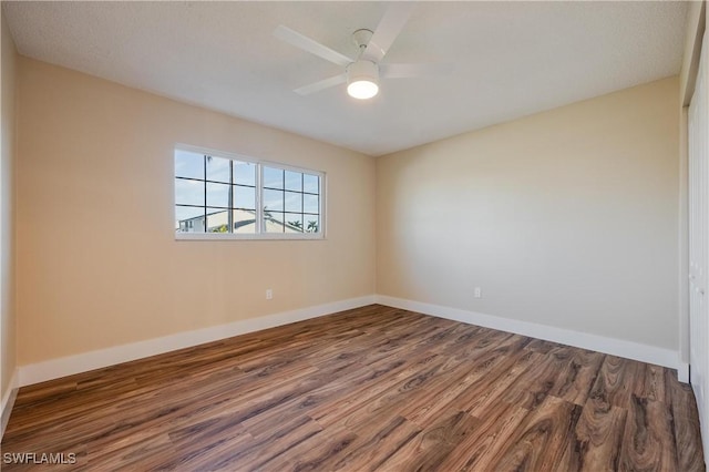 empty room featuring baseboards, ceiling fan, and dark wood finished floors