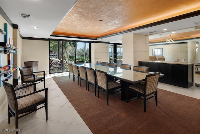 tiled dining room with french doors, plenty of natural light, and a raised ceiling