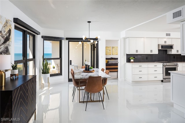 kitchen featuring tasteful backsplash, hanging light fixtures, white cabinetry, stainless steel appliances, and a water view