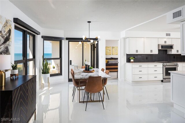 kitchen featuring stainless steel appliances, a water view, tasteful backsplash, white cabinets, and decorative light fixtures