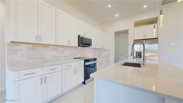 kitchen with light stone counters, stainless steel appliances, tasteful backsplash, and white cabinets