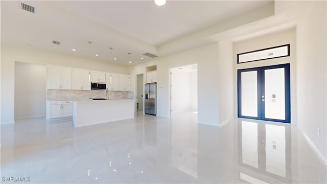 kitchen with french doors, stainless steel appliances, a center island with sink, and white cabinets