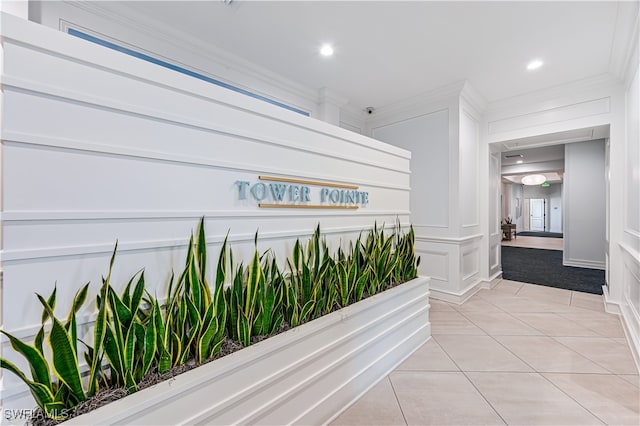 hall featuring light tile patterned floors and crown molding