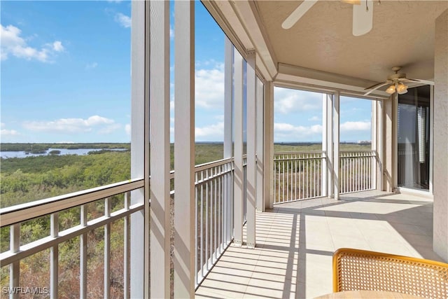 unfurnished sunroom featuring ceiling fan and a water view