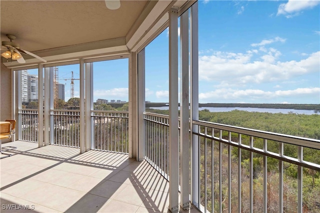 unfurnished sunroom featuring ceiling fan, a water view, and a healthy amount of sunlight