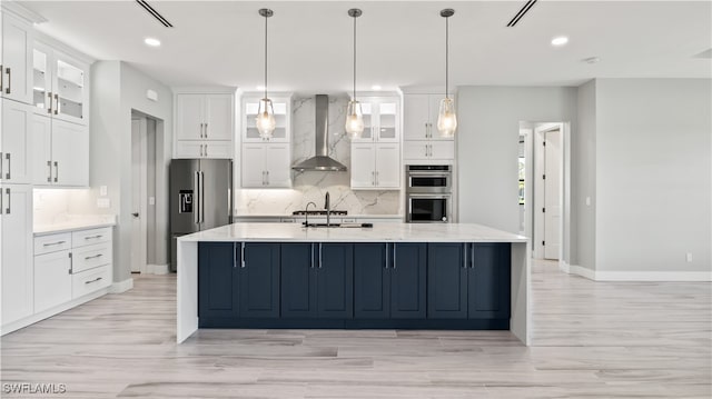 kitchen with wall chimney range hood, white cabinets, and stainless steel appliances