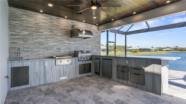 view of patio with an outdoor kitchen, glass enclosure, ceiling fan, area for grilling, and a water view