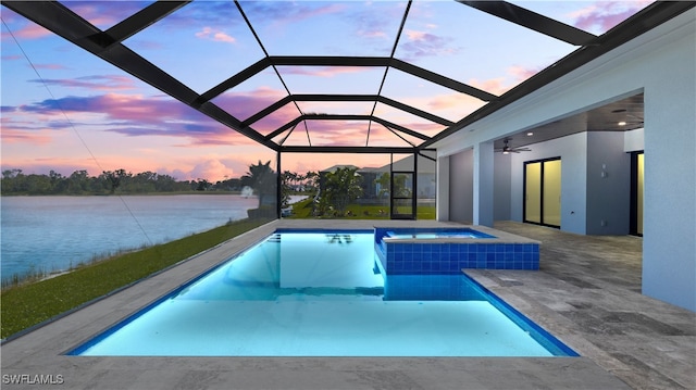 pool at dusk with a patio area, ceiling fan, a water view, and a lanai