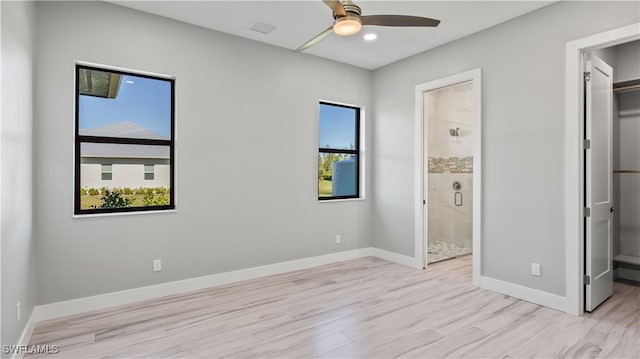 unfurnished bedroom with light hardwood / wood-style flooring, a spacious closet, connected bathroom, and ceiling fan