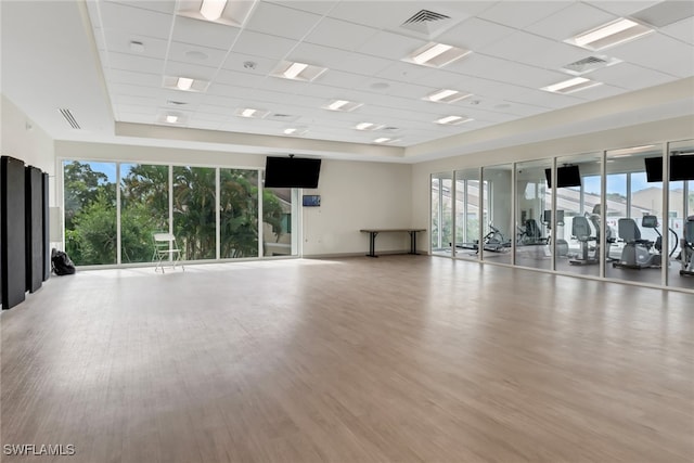 workout area with light hardwood / wood-style floors and a paneled ceiling