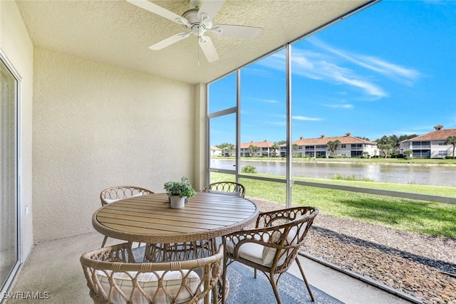 sunroom / solarium with ceiling fan and a water view