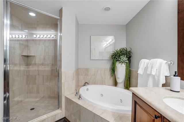 bathroom with a tub with jets, a shower stall, and vanity