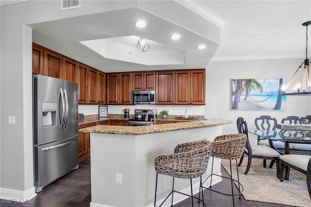 kitchen with brown cabinets, decorative light fixtures, visible vents, appliances with stainless steel finishes, and a peninsula