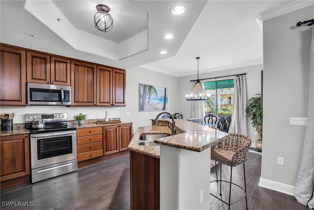 kitchen featuring light stone counters, a breakfast bar area, stainless steel appliances, a sink, and a center island with sink