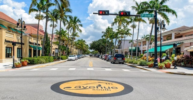 view of street featuring curbs, traffic lights, sidewalks, and street lighting