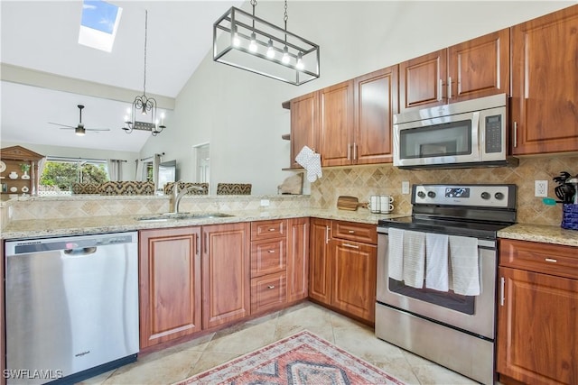 1039 Cardinal St, Naples, FL 34104 - kitchen with a skylight, brown cabinetry, decorative backsplash, pendant lighting, and appliances with stainless steel finishes