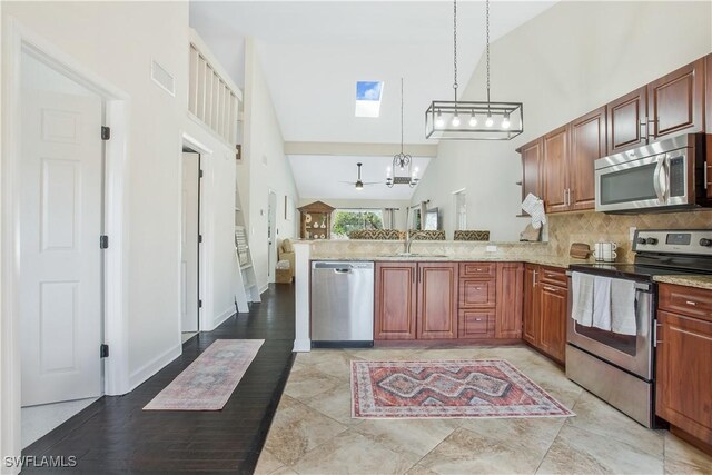 1039 Cardinal St, Naples, FL 34104 - kitchen featuring a sink, a skylight, decorative backsplash, a peninsula, and appliances with stainless steel finishes