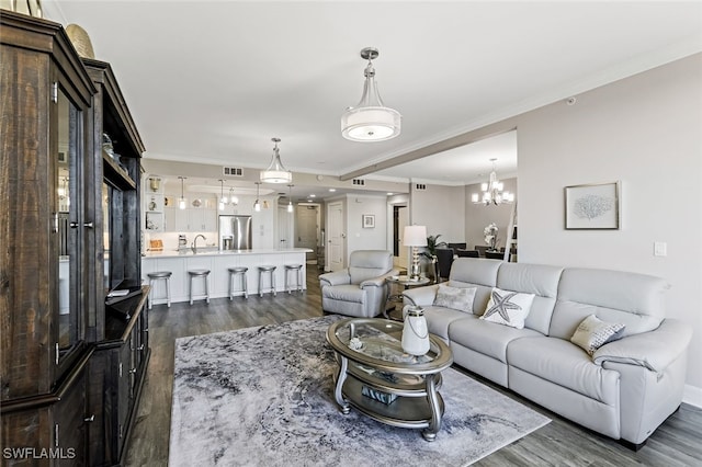 living area with an inviting chandelier, crown molding, visible vents, and dark wood-style flooring